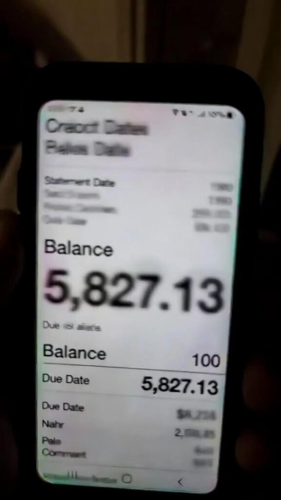 Candid phone photo of a credit card statement in dim lighting, everything blurred except the alarming balance of $5,827.13.