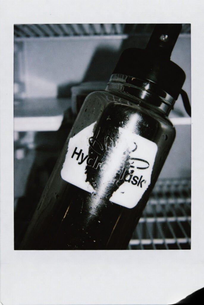 Fuzzy instant-photo style — beat-up Hydro Flask, peeling logo, fridge dew (10 words)